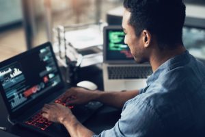 Man, typing and programmer on laptop in office workplace for data, analysis or statistics. IT, computer and male coder, engineer or person programming, coding and software development for information.